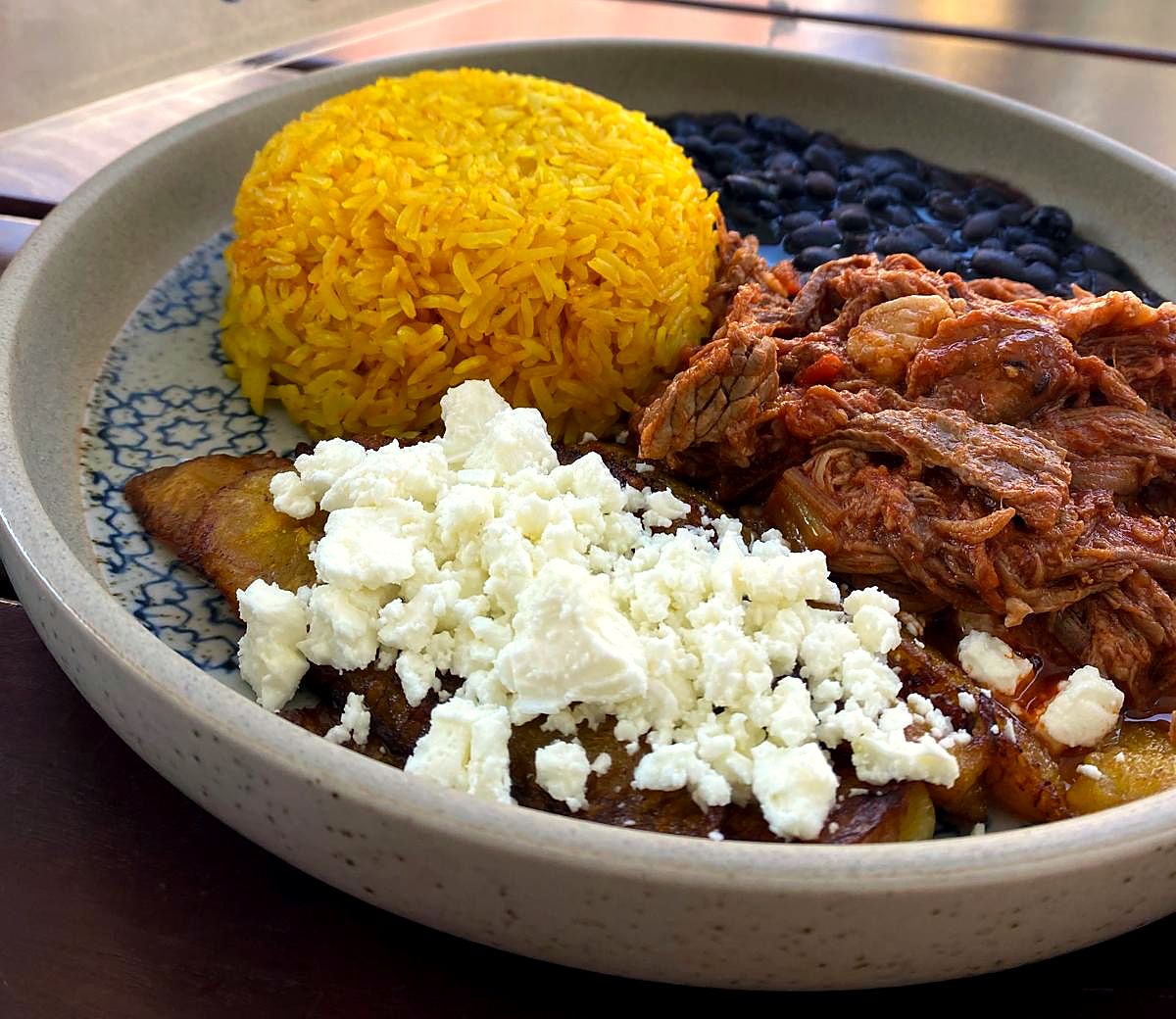 Pabellón Criollo mit Kurkumareis, schwarzen Bohnen, Carne Mechada und Feta